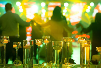 Foreground focus vases on glass table with dancing people at party