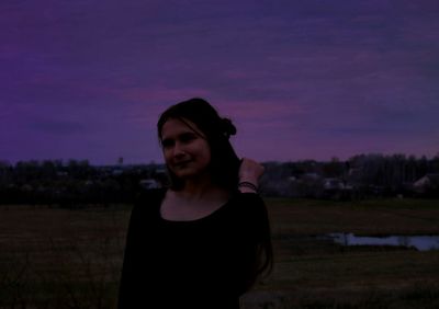 Portrait of young woman standing against sky