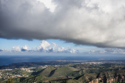 Aerial view of city by sea against storm clouds