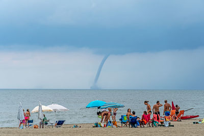 People at beach against sky