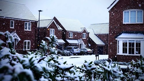 Snow covered houses and buildings against sky