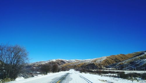 Snow covered landscape against clear blue sky