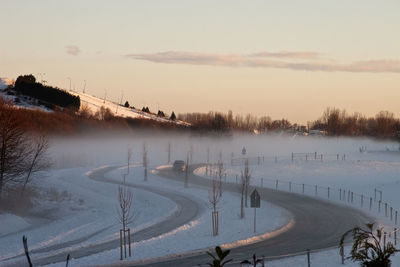 Scenic view of snow covered lake against sky during sunset