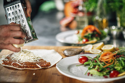 Preparing vegetarian burrito - chef grating cheese with a grater