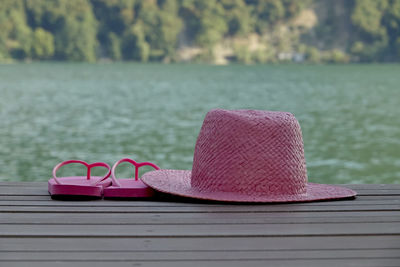 Close-up of pink shoes on wood against lake