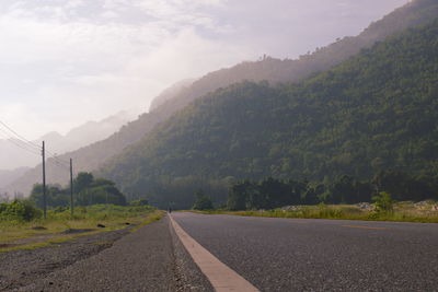 Empty road by mountains against sky