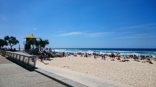 People at beach against blue sky