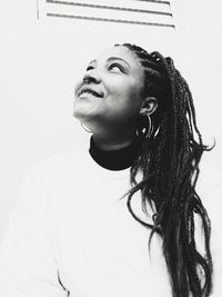 Low angle portrait of woman looking away against wall