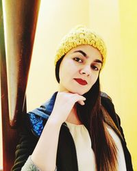 Close-up portrait of young woman standing against wall