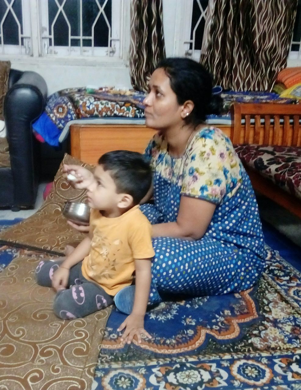 HAPPY MOTHER AND DAUGHTER SITTING ON COUCH