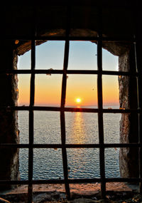 Close-up of sea seen through window during sunset