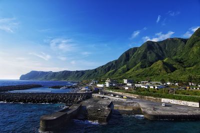 Scenic view of river by mountains against blue sky