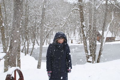 Young woman standing on snowcapped field during snowfall