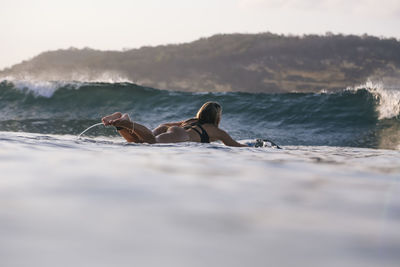 Female surfer in the ocean at sunset