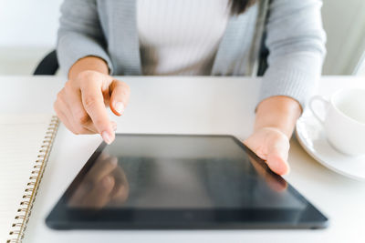 Midsection of man using smart phone on table