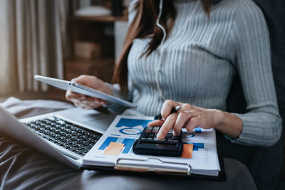 Midsection of woman using digital tablet at table