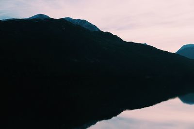 Scenic view of lake and mountains against sky during sunset