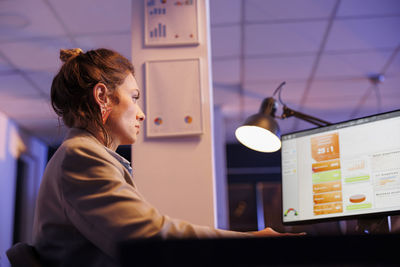 Side view of young woman using mobile phone at home