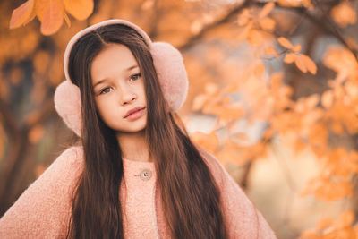 Portrait of kid girl 10-12 year old with long hair wear casual jacket in park over yellow leaves