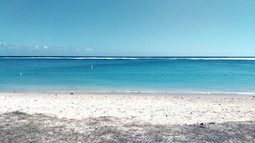 View of calm beach against clear blue sky