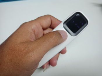 Close-up of hand holding smart phone over white background