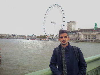 Portrait of smiling man standing by river against sky