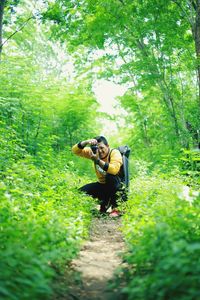 Man photographing while crouching in forest