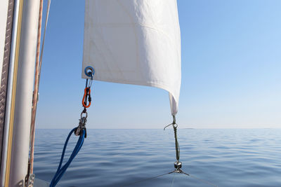 Close-up of sailboat on sea against clear blue sky