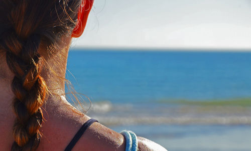 Midsection of woman looking at sea against sky