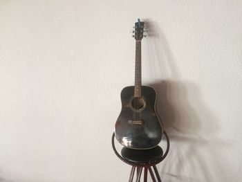 Close-up of guitar on table against wall