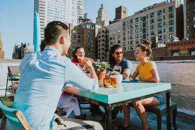 People sitting in restaurant against buildings in city