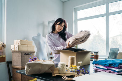 Small business owner woman packs the goods in eco packaging in office, shop.