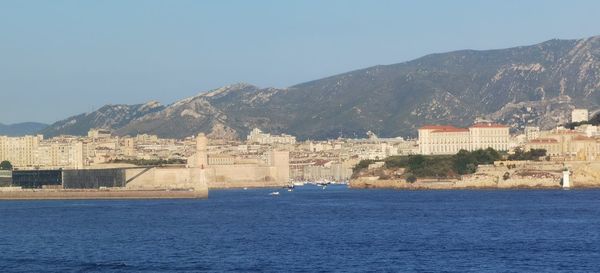 Scenic view of sea by buildings against clear sky