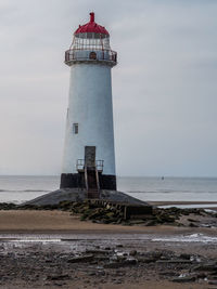 Lighthouse by sea against sky