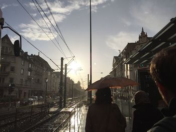 People at railroad station against sky