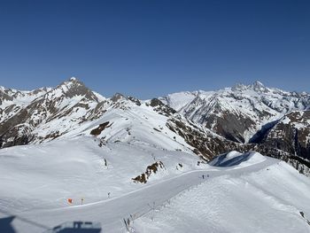 Scenic view of snowcapped mountains against clear blue sky
