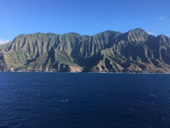 Scenic view of sea and mountains against clear blue sky