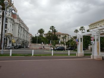 Road by buildings in city against sky