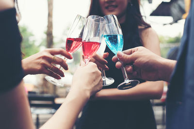 Midsection of friends toasting drinks at bar