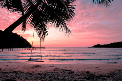 Silhouette palm trees on beach against sky during sunset