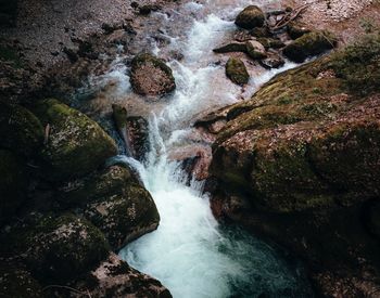 High angle view of stream flowing amidst rocks