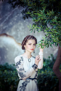 Young woman standing against plants