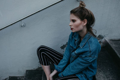 Thoughtful woman wearing denim jacket while sitting outdoors