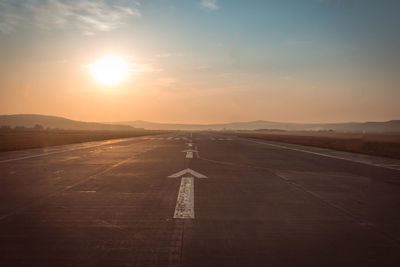 Airport runway against sky during sunset