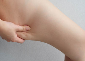 Cropped image of woman pinching thigh