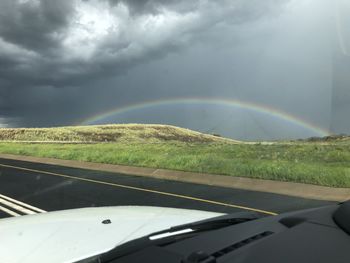 Rainbow over road seen through car windshield