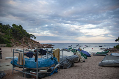 Deck chairs on beach against sky