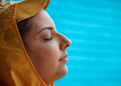 Side view of woman with wet face against blue window