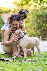 Mother and daughter playing with dog at backyard