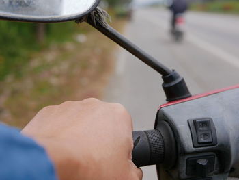 Cropped hand of man motor scooter on road